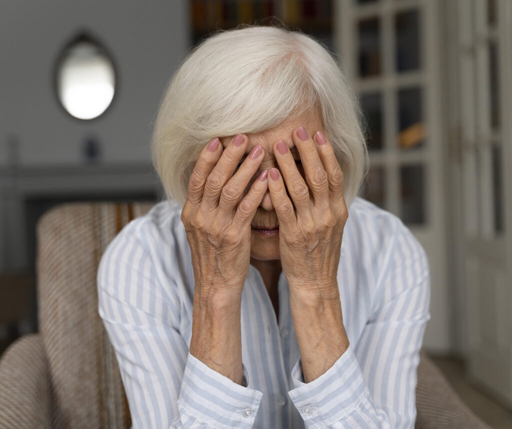 Ältere Frau hält sich besorgt das Gesicht in den Händen – Symbolbild für seelische Belastung und Demenzbetreuung durch den Pflegedienst Aronia